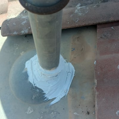 צינור על גג עם חומר איטום לבן סביבו