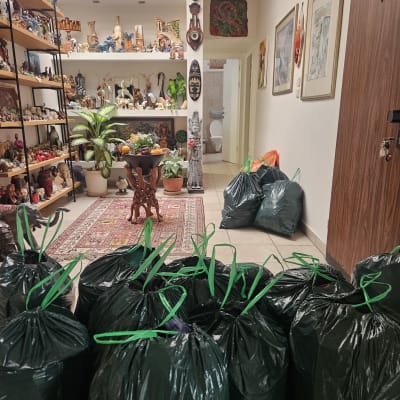 שקיות אשפה שחורות עם ידיות ירוקות במסדרון בית