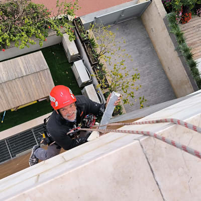 אדם עם קסדה אדומה מטפס על חבל עם כלי עבודה