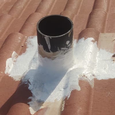 צינור שחור על גג רעפים עם חומר איטום לבן