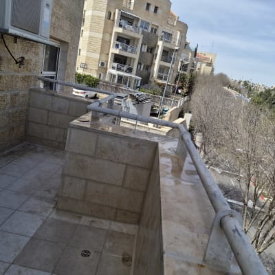 מרפסת עם ריצוף ואיטום, מבנים ברקע