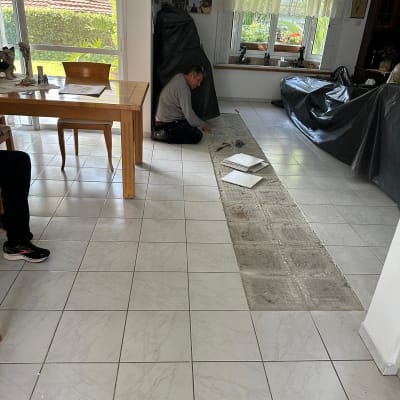 אדם מתקין אריחים על רצפה בחדר עם כלים