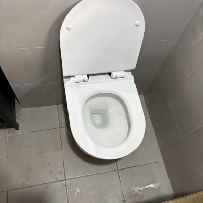 אסלה לבנה מותקנת בחדר אמבטיה עם רצפת אריחים אפורה