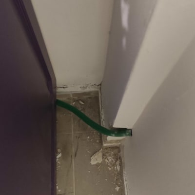 צינור ירוק בקיר עם שאריות טיח על הרצפה