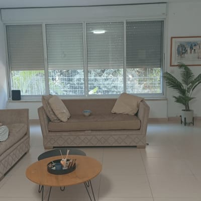 סלון עם ספות ותריסים סגורים בחלון גדול