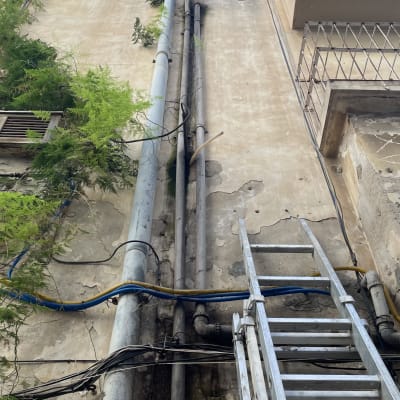 סולם מתכת ליד צינורות על קיר בניין