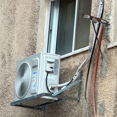 יחידת מיזוג אוויר מותקנת על קיר חיצוני ליד חלון