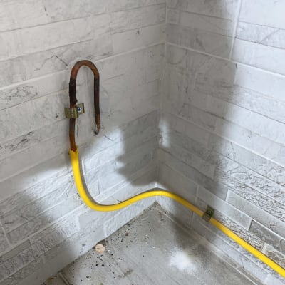 צינור גז צהוב מותקן על קיר לבנים