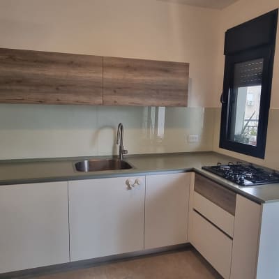 מטבח עם חיפוי זכוכית מעל השיש והכיור