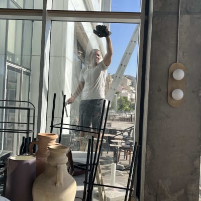 אדם מנקה חלון עם סמרטוט, סולם ברקע