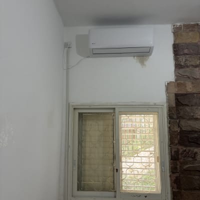 מזגן מותקן על קיר ליד חלון עם סורגים
