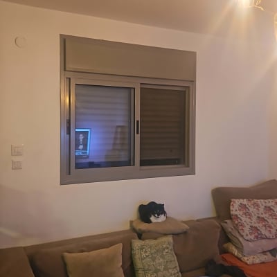 חלון עם תריסים בסלון עם ספה וכריות