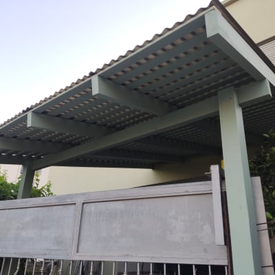 פרגולה מעץ עם גג מתכת ליד גדר