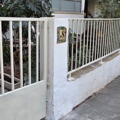 גדר לבנה עם שער ליד מדרכה