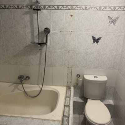 חדר אמבטיה עם אמבטיה, שירותים ואריחים על הקיר