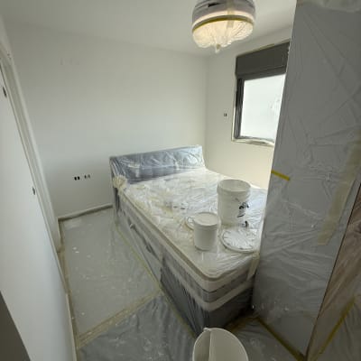 חדר מכוסה בניילון עם דליי צבע על המיטה