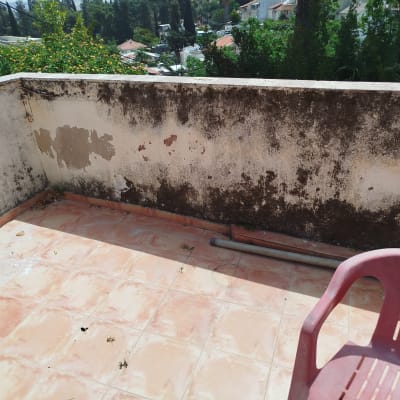 מרפסת עם קיר מתקלף וצינור על הרצפה