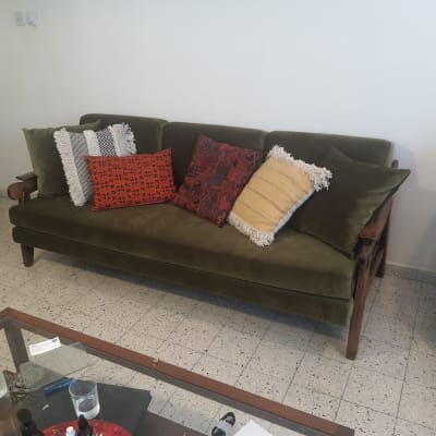 ספה ירוקה עם כריות צבעוניות על רצפת אריחים