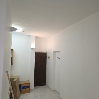 קיר צבוע בלבן עם כלים לצביעה על הרצפה