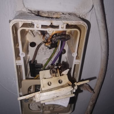 שקע חשמלי פתוח עם חוטים חשופים ונזק חום