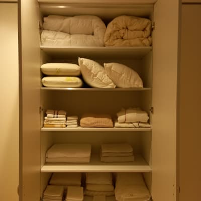 ארון עם מצעים מקופלים ומסודרים על מדפים
