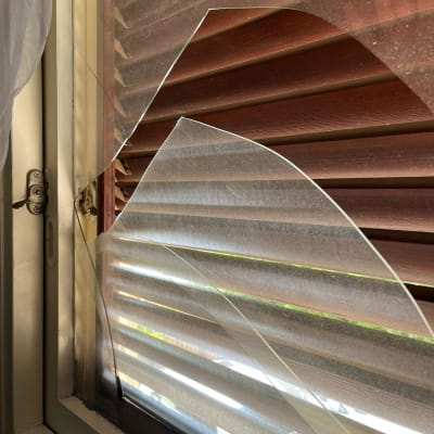 זכוכית שבורה על חלון עם תריסים חומים