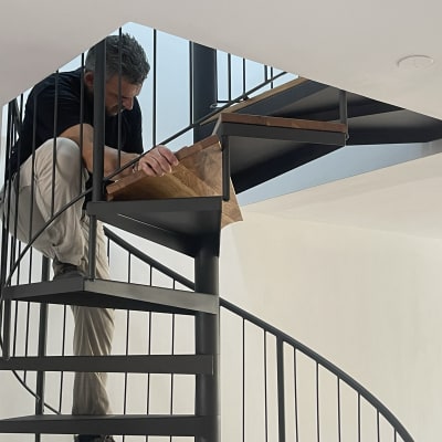נגר עובד על מדרגות לולייניות מעץ ומתכת