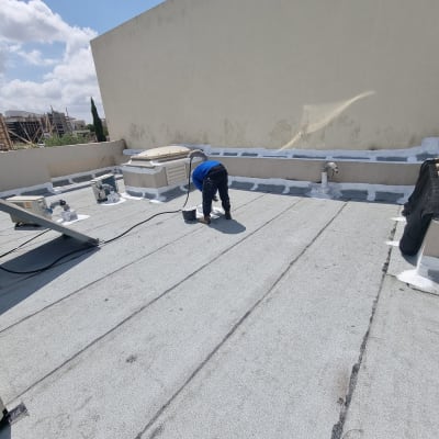 אדם מורח חומר איטום על גג שטוח