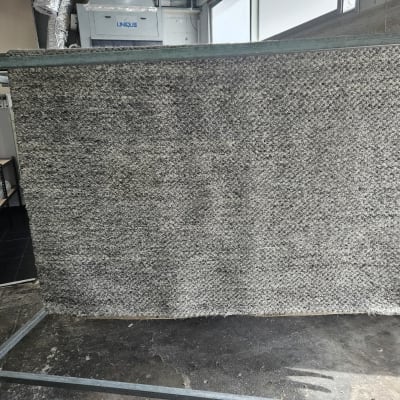 שטיח אפור תלוי לייבוש על מתקן מתכת