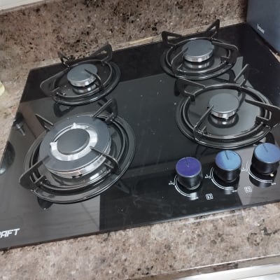 כיריים גז עם ארבעה מבערים על משטח שיש.