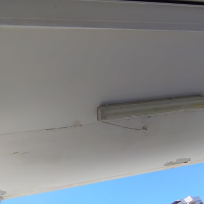 תאורת פלורסנט תלויה על תקרה עם חוטים חשופים