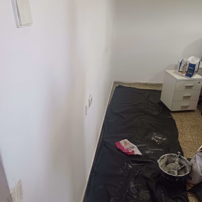 קיר צבוע עם יריעת מגן ודלי צבע על הרצפה