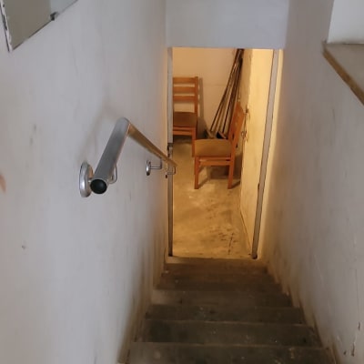 מדרגות עם מעקה מתכת וחדר עם כיסאות