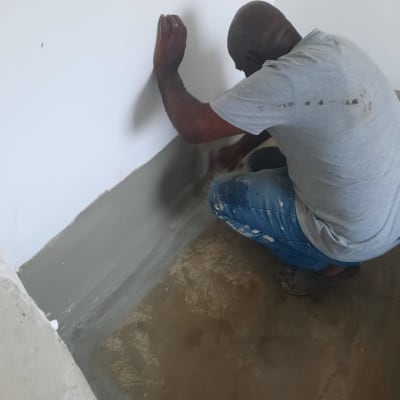 אדם מורח חומר איטום על קיר ורצפה