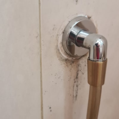 צינור מים מחובר לקיר עם כתמי רטיבות