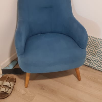 כיסא כחול על רצפת עץ עם נעליים בצד