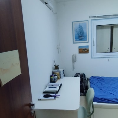 מזגן מותקן על קיר בחדר שינה עם מיטה ושולחן כתיבה