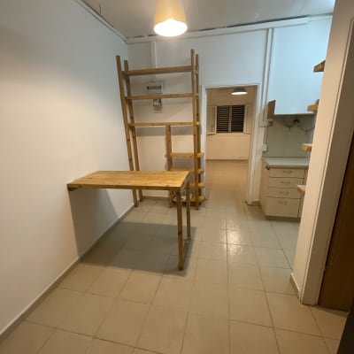 חדר עם קירות לבנים, שולחן עץ ומדפים