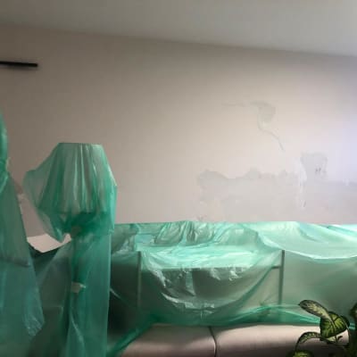 קיר עם תיקוני צבע ויריעות פלסטיק לכיסוי רהיטים