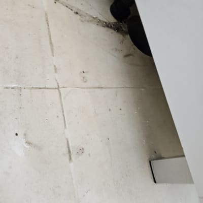 רצפה עם לכלוך ליד צינור שחור מתחת לכיור