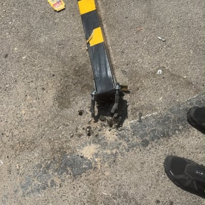 מחסום חניה שבור על הכביש עם נעליים לידו