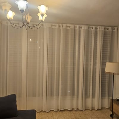 סלון עם וילונות, ספה, מנורה וטלוויזיה על הקיר