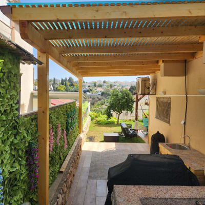 פרגולה מעץ עם גינה ירוקה ברקע