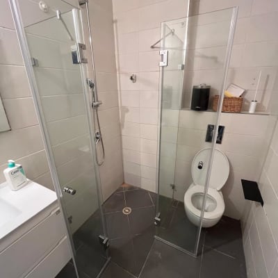 מקלחון זכוכית עם ראש מקלחת מתכת על קיר אריחים