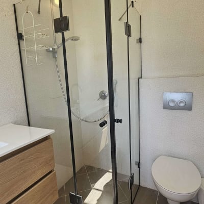 מקלחון זכוכית עם ראש מקלחת וכיור עץ