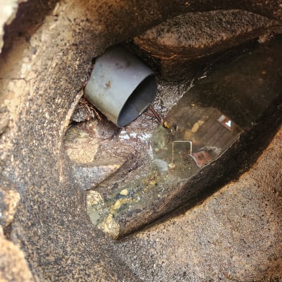 צינור פלסטיק אפור בתוך חור באדמה