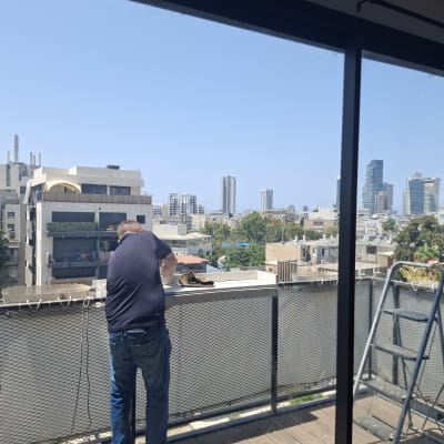 אדם עובד על מרפסת עם נוף לעיר דרך חלון זכוכית