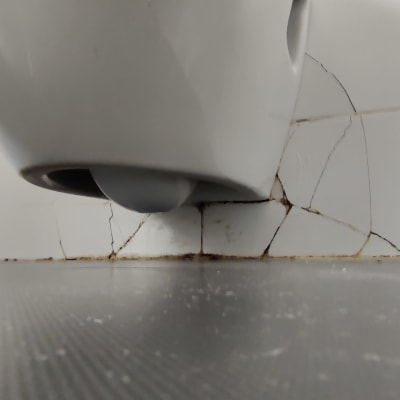 אריחים סדוקים ליד מתקן תלוי על קיר