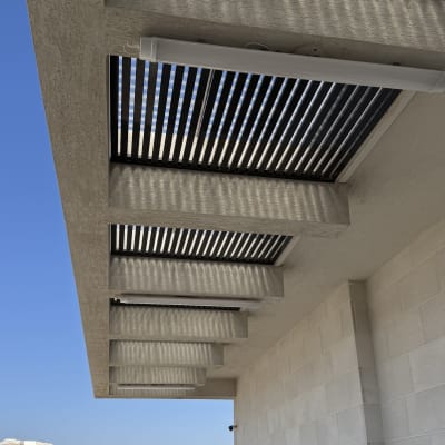 פרגולה מאלומיניום על מרפסת עם כיסאות ושולחן.