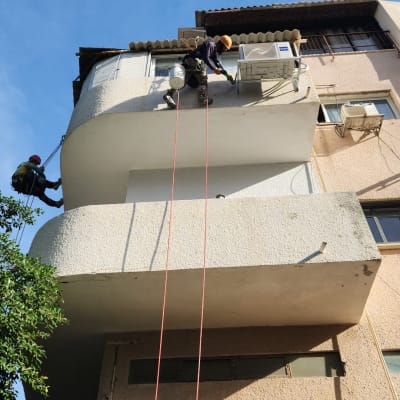 עובדים על חבלים אוטמים קיר חיצוני של בניין